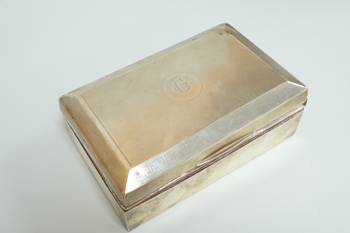 An engine turned silver rectangular cigarette box, 14.1cm and two mid 20th century engine turned silver cigarette cases.